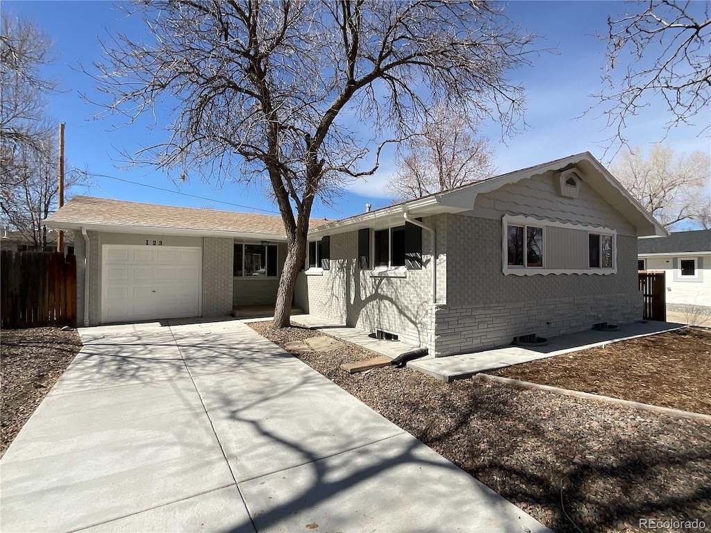 ranch-style house with concrete driveway, an attached garage, fence, and brick siding