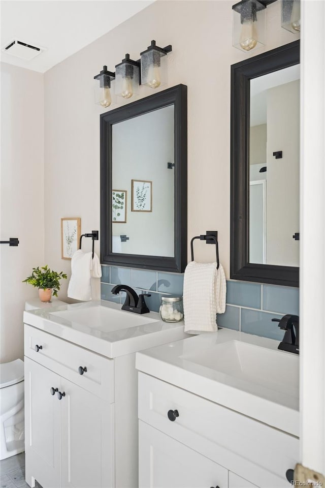 bathroom with vanity, toilet, and decorative backsplash
