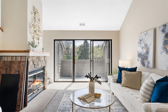 carpeted living room with a stone fireplace and lofted ceiling