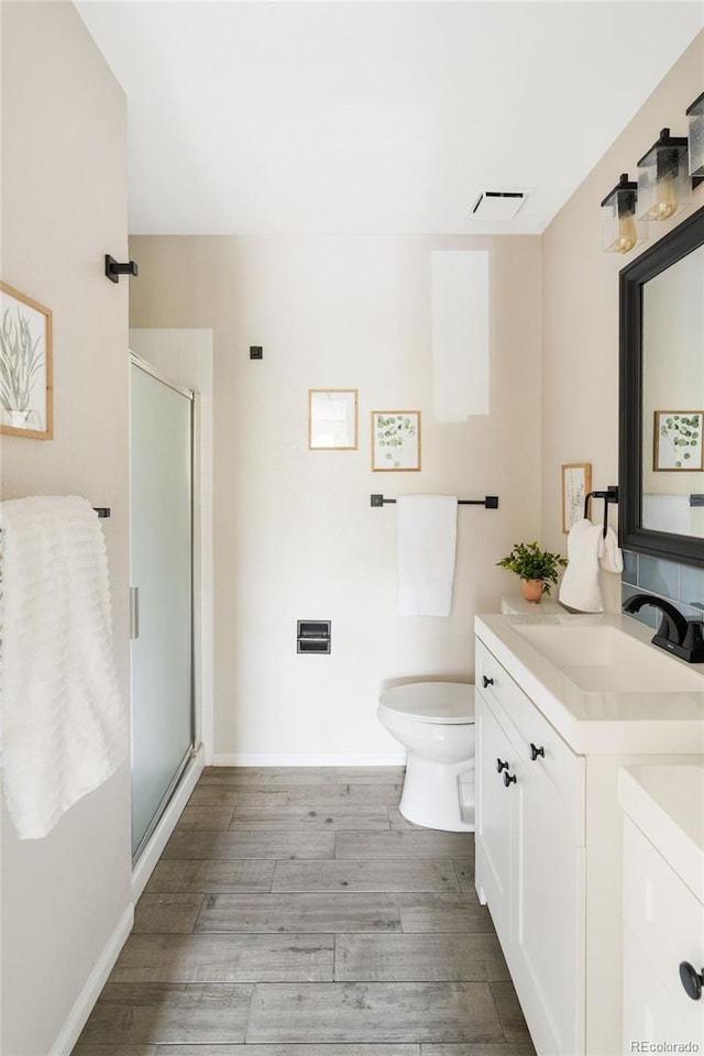 full bath with a stall shower, wood finished floors, vanity, toilet, and baseboards
