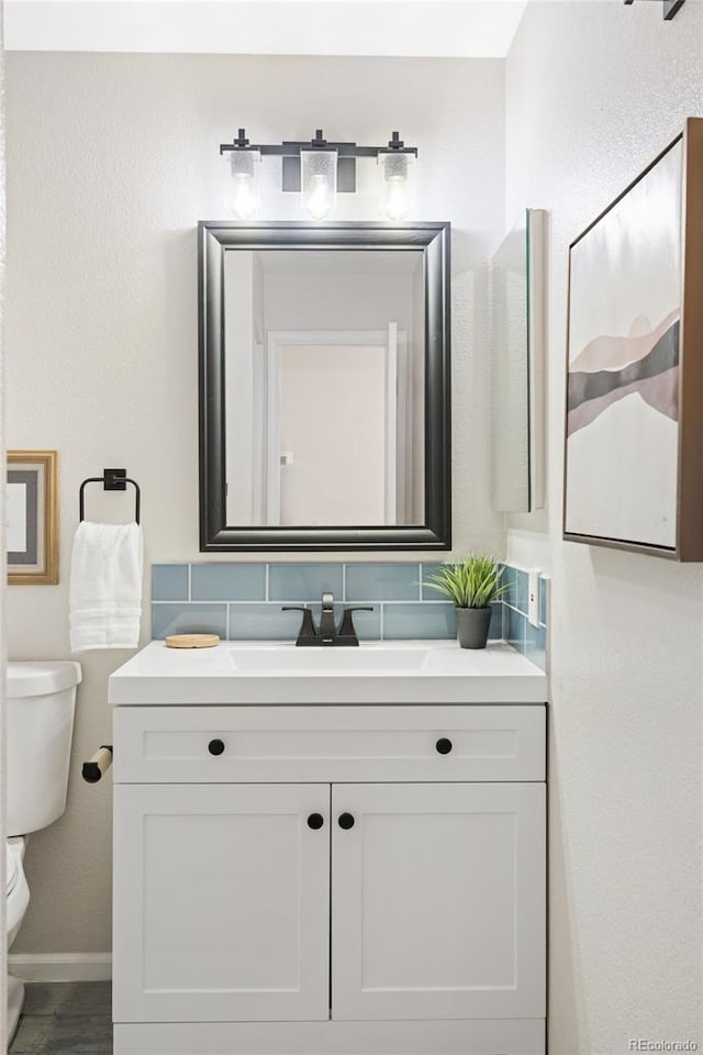 half bathroom featuring toilet, vanity, and baseboards
