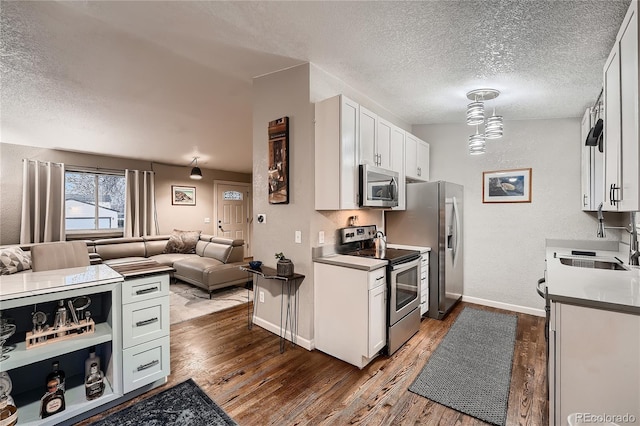 4063 S Quintero Way, Aurora, CO 80013 - kitchen featuring appliances with stainless steel finishes, open floor plan, dark wood-type flooring, a sink, and baseboards