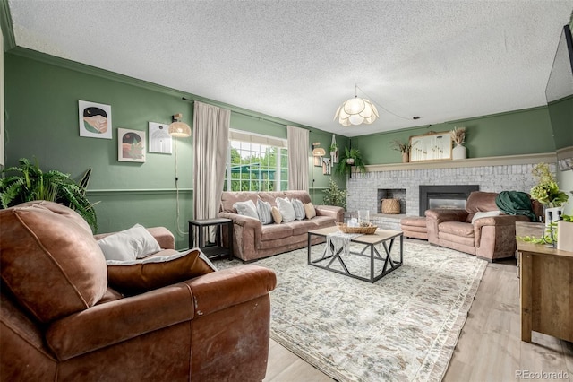 16051 E Alabama Dr, Aurora, CO 80017 - living room with a textured ceiling, a brick fireplace, light wood finished floors, and ornamental molding