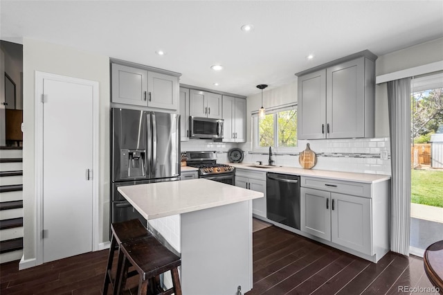 kitchen featuring a wealth of natural light, a sink, dark wood-type flooring, stainless steel appliances, and gray cabinets