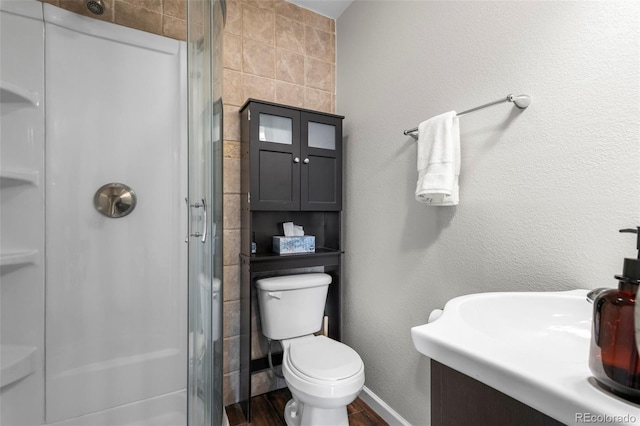 full bath with toilet, wood finished floors, vanity, a shower stall, and baseboards
