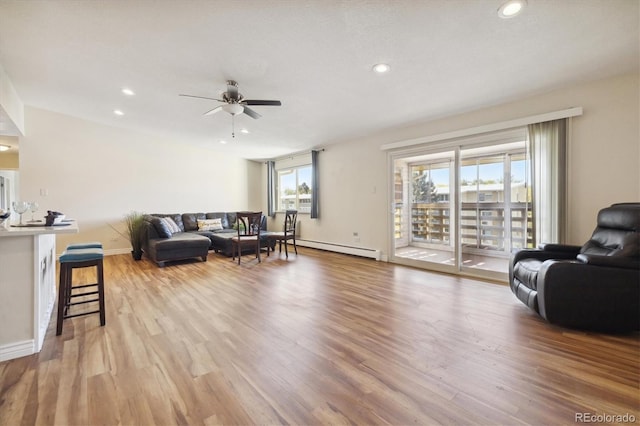 living room with light hardwood / wood-style floors, baseboard heating, and ceiling fan