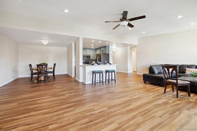 living room featuring a textured ceiling, light wood-type flooring, and ceiling fan