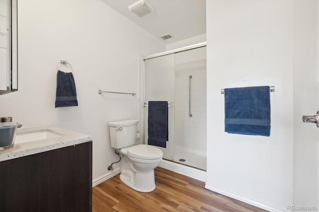 bathroom featuring vanity, toilet, wood-type flooring, and a shower with shower door