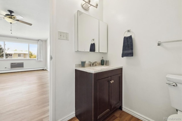 bathroom with hardwood / wood-style floors, a baseboard radiator, toilet, a wall mounted air conditioner, and vanity