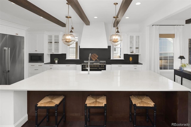 6288 N Dallas St, Denver, CO 80238 - kitchen featuring high end appliances, premium range hood, tasteful backsplash, beamed ceiling, and a spacious island