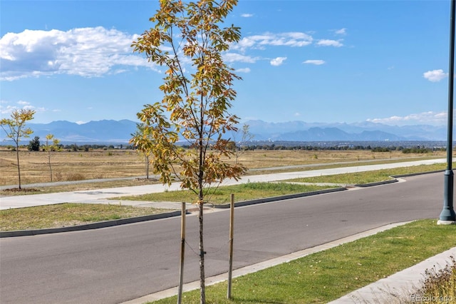 6288 N Dallas St, Denver, CO 80238 - view of asphalt road with a mountain view, curbs, and a view of countryside