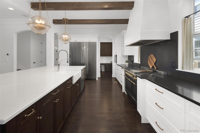 6288 N Dallas St, Denver, CO 80238 - kitchen featuring custom exhaust hood, high end appliances, arched walkways, beam ceiling, and dark wood-style flooring