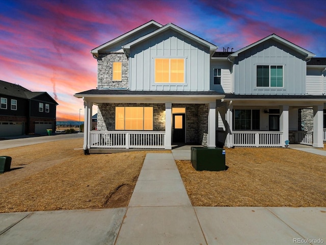 view of front of property featuring board and batten siding, a porch, and stone siding