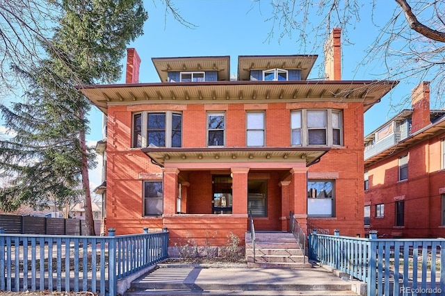 view of front of property featuring brick siding, a porch, a chimney, and fence