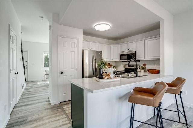 2642 Devonshire Ct, Denver, CO 80229 - kitchen featuring stainless steel appliances, light wood finished floors, a peninsula, baseboards, and light countertops