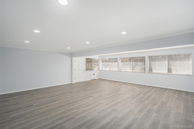 spare room with radiator, crown molding, baseboards, and wood finished floors