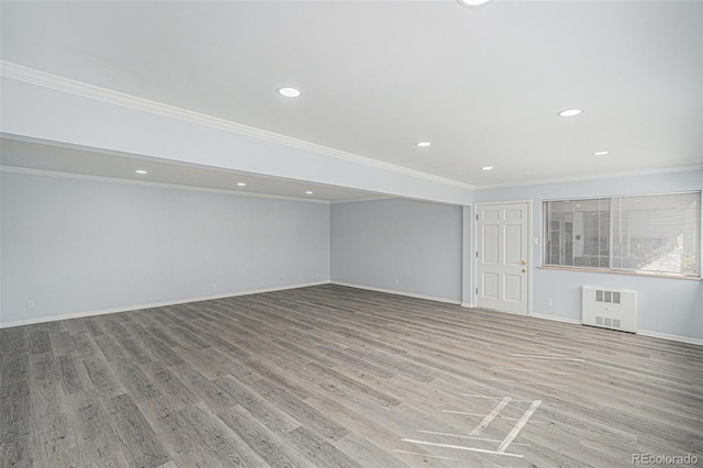 unfurnished living room with ornamental molding, baseboards, radiator heating unit, and wood finished floors