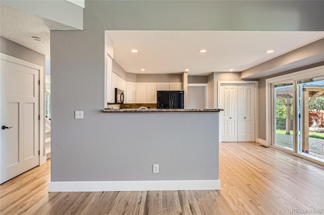 5370 S Jebel St, Centennial, CO 80015 - kitchen featuring black fridge, white cabinetry, light wood finished floors, a peninsula, and dark stone countertops