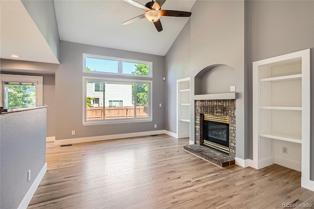 5370 S Jebel St, Centennial, CO 80015 - unfurnished living room featuring high vaulted ceiling, a glass covered fireplace, a ceiling fan, wood finished floors, and built in shelves
