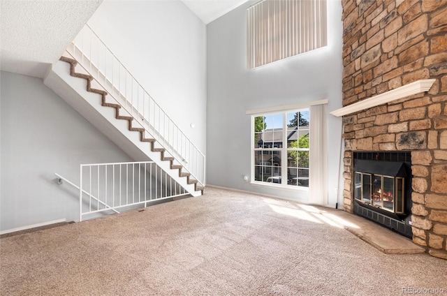 2973 W 81st Ave Unit D, Westminster, CO 80031 - unfurnished living room featuring carpet floors, a fireplace, stairway, and a towering ceiling