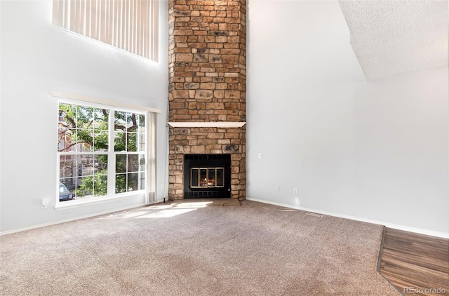 2973 W 81st Ave Unit D, Westminster, CO 80031 - unfurnished living room featuring a towering ceiling, a stone fireplace, carpet, and a textured ceiling