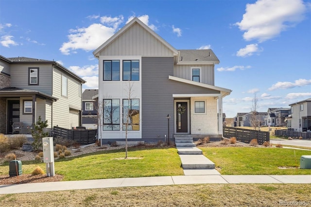 view of front of property featuring board and batten siding, fence, and a front lawn