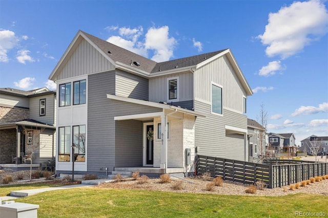view of front facade with a residential view, board and batten siding, a front yard, and fence