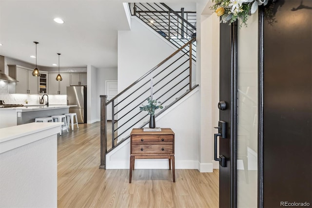 foyer entrance with baseboards, light wood-type flooring, recessed lighting, and stairs