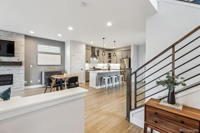 living area with light wood-type flooring, recessed lighting, a fireplace, and stairway
