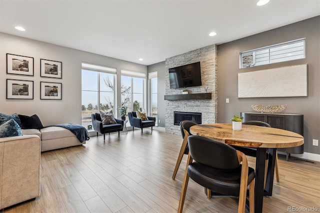 dining area with recessed lighting, a fireplace, light wood-style flooring, and baseboards