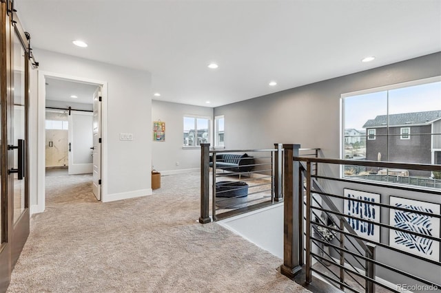 hall featuring carpet flooring, recessed lighting, an upstairs landing, and a barn door