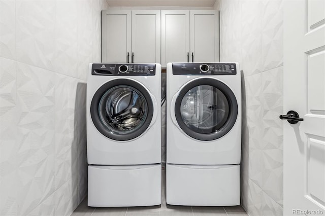 washroom featuring cabinet space, washer and dryer, and light tile patterned flooring