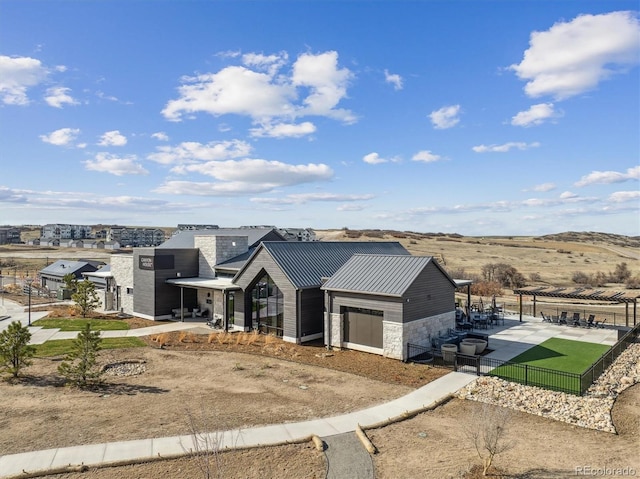 view of front of house featuring a chimney, stone siding, a standing seam roof, metal roof, and fence