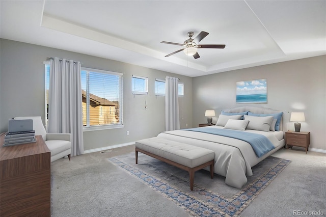 bedroom featuring a raised ceiling, ceiling fan, and carpet floors