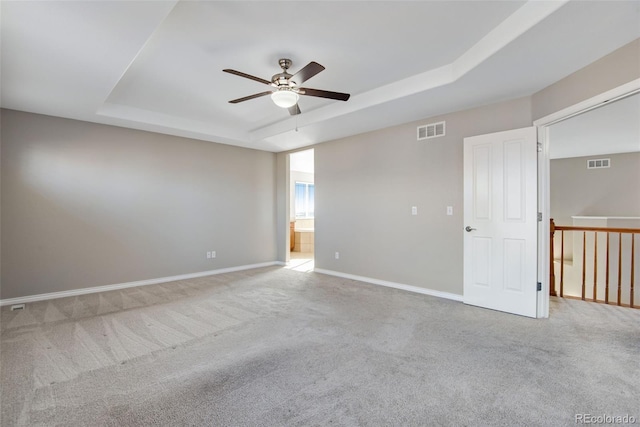 carpeted spare room featuring a raised ceiling and ceiling fan