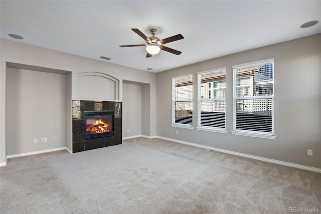 unfurnished living room featuring a tile fireplace, light colored carpet, and ceiling fan