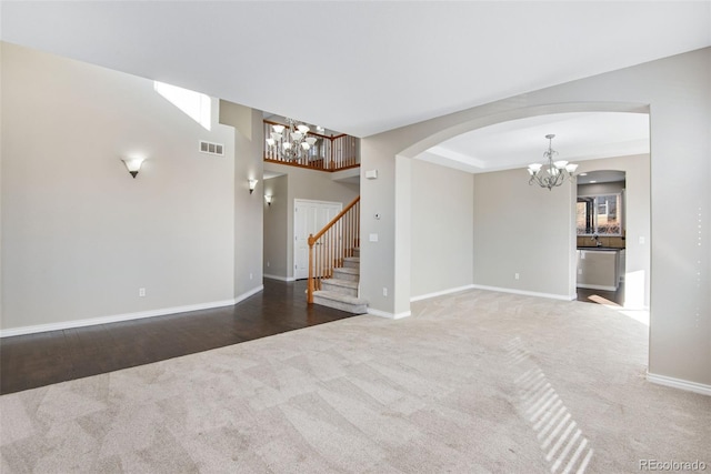 unfurnished living room with carpet flooring and an inviting chandelier