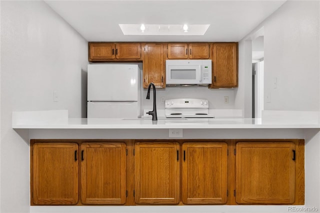 kitchen featuring light countertops, white appliances, a skylight, and brown cabinets