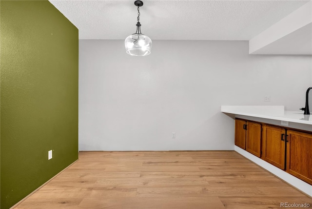 unfurnished dining area featuring light wood-style flooring and a textured ceiling