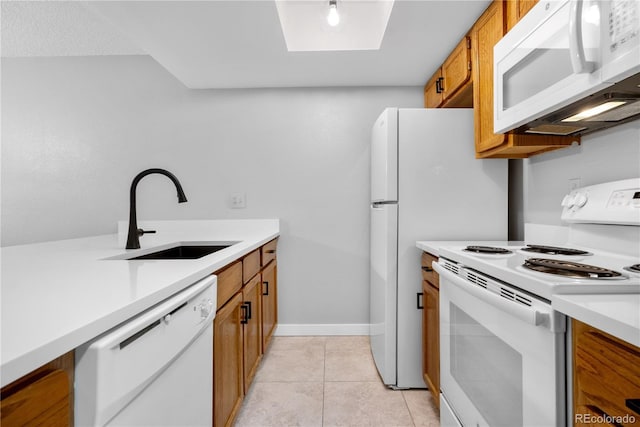 kitchen with white appliances, brown cabinets, light countertops, a sink, and light tile patterned flooring