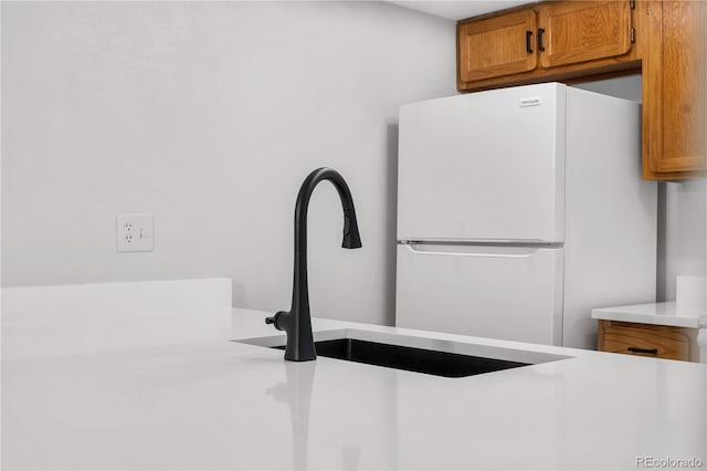 details featuring brown cabinets, light countertops, a sink, and freestanding refrigerator