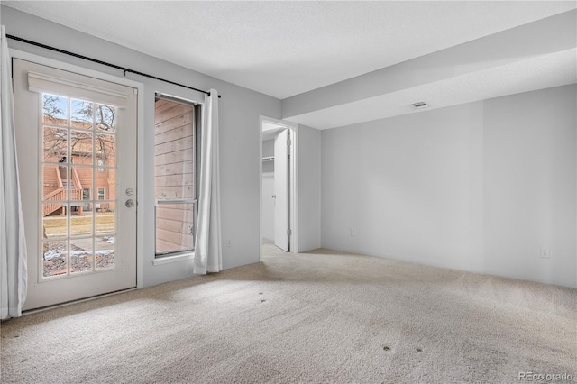 unfurnished room featuring light carpet, a textured ceiling, and visible vents