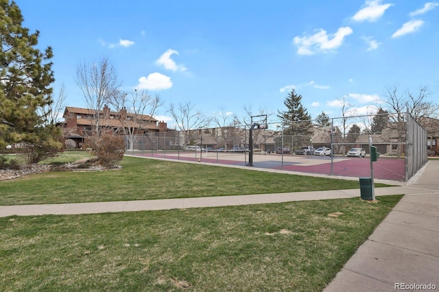 view of community featuring a tennis court, community basketball court, fence, and a yard