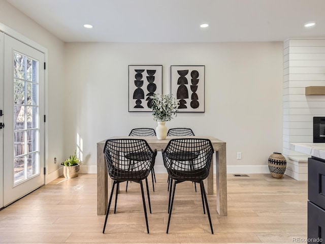 dining area with a fireplace and light hardwood / wood-style flooring