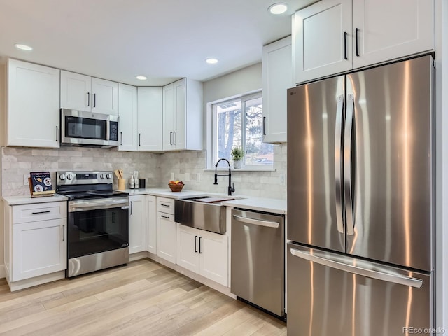 kitchen featuring white cabinets, appliances with stainless steel finishes, tasteful backsplash, and sink