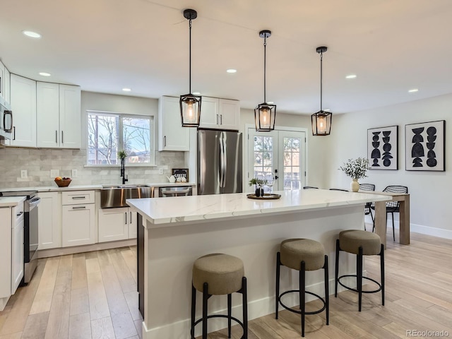 kitchen with white cabinets, stainless steel appliances, a center island, and hanging light fixtures