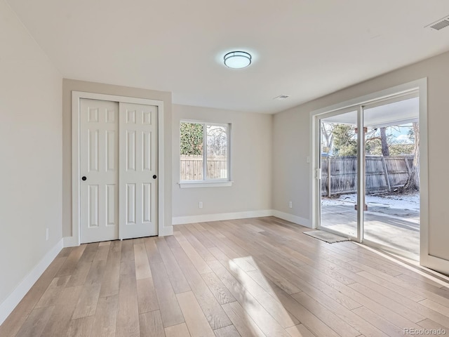 interior space with access to outside, a closet, light hardwood / wood-style flooring, and multiple windows