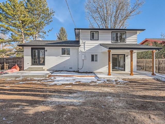 snow covered rear of property with french doors and a patio area