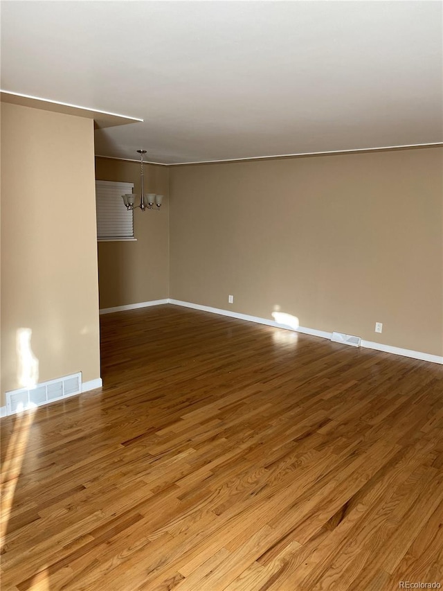 spare room featuring light hardwood / wood-style floors and a notable chandelier