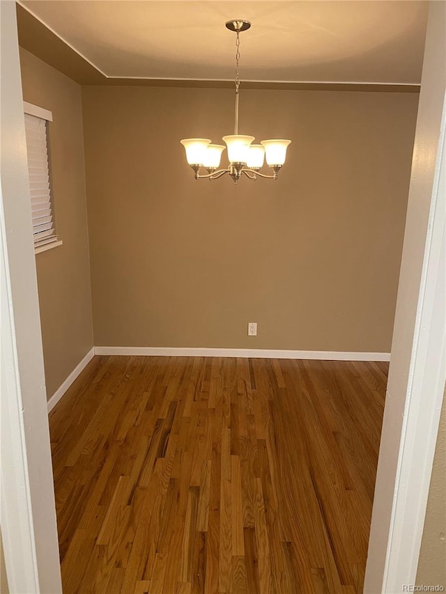 unfurnished dining area with wood-type flooring and a notable chandelier